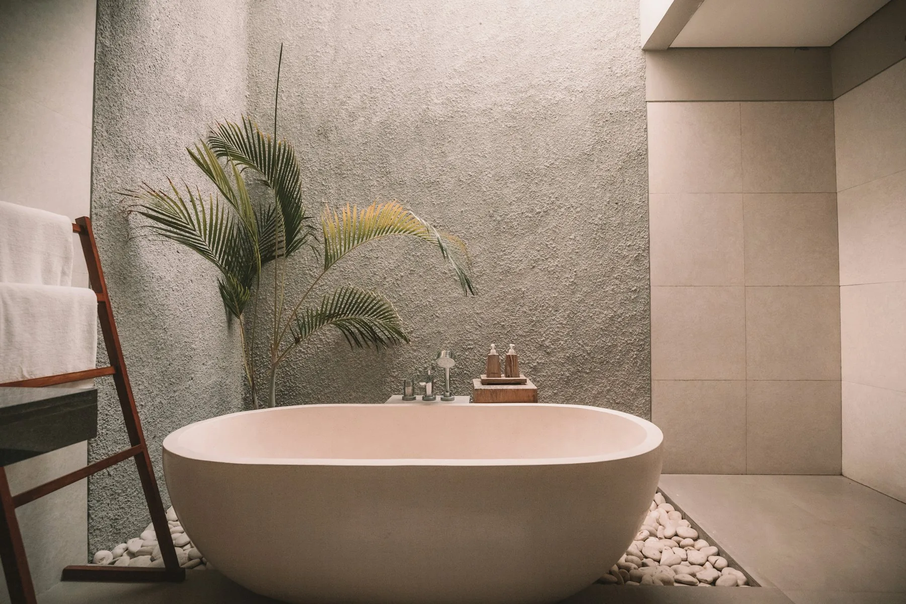 Spa bathroom with a freestanding stone bath and warm neutral surfaces